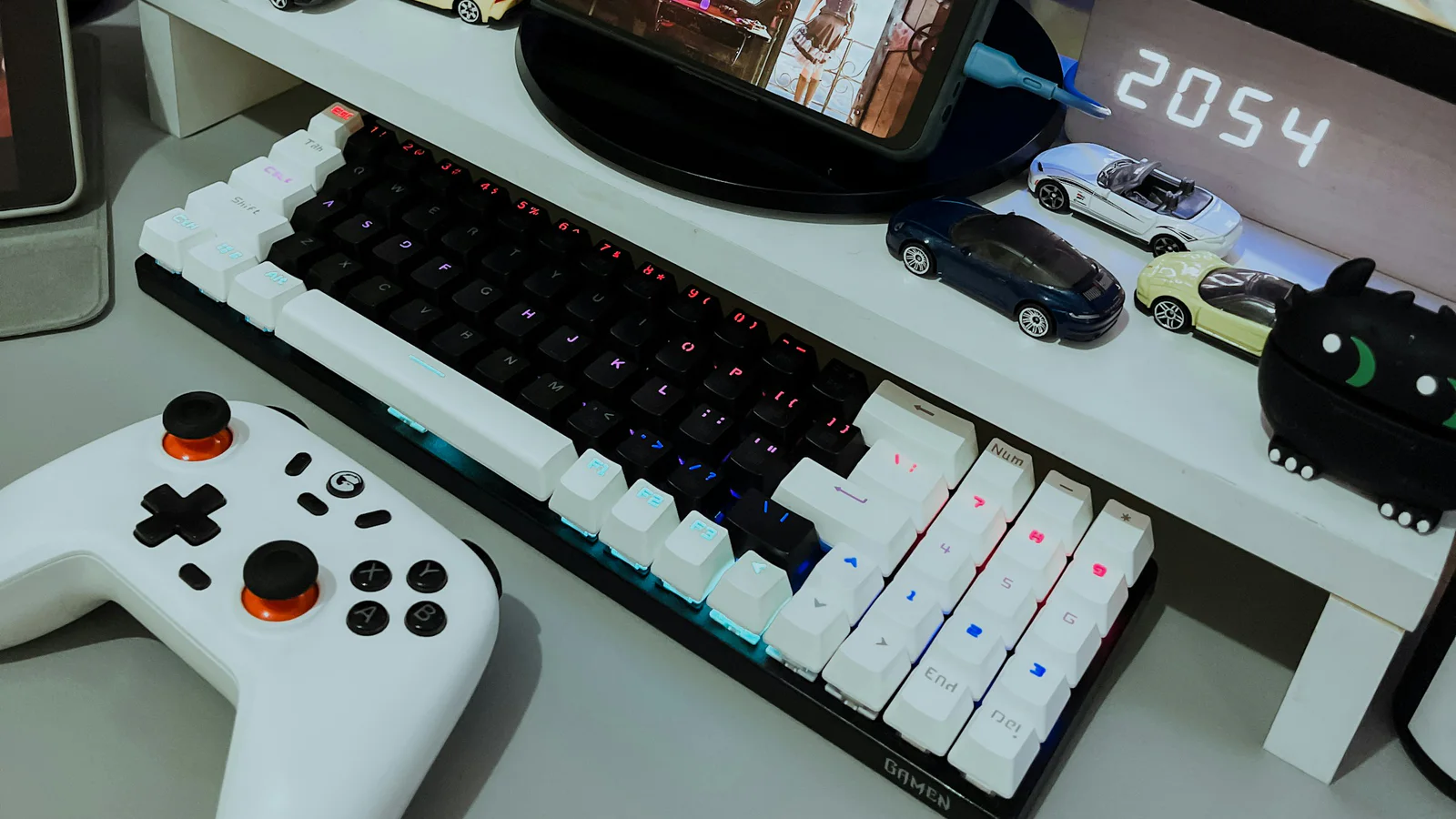 Real gaming desk with controllers, keyboard, display, and a game running on a phone